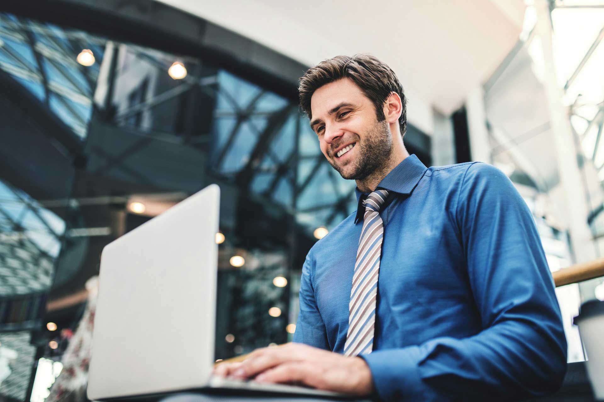 Giovane businessman al lavoro sul suo computer portatile all'interno di un grande ufficio